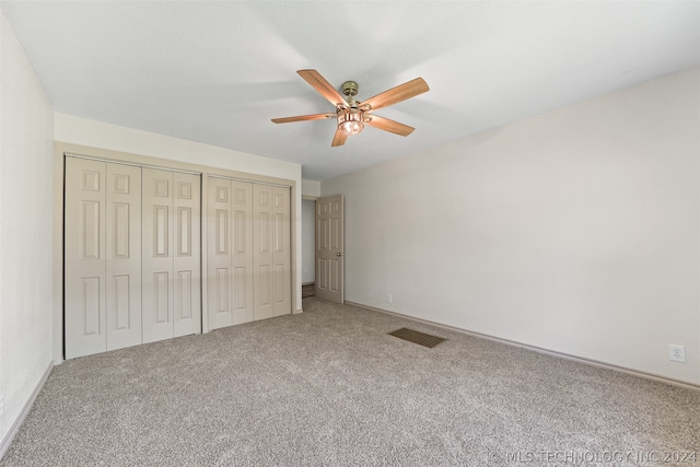 unfurnished bedroom with two closets, ceiling fan, and carpet flooring