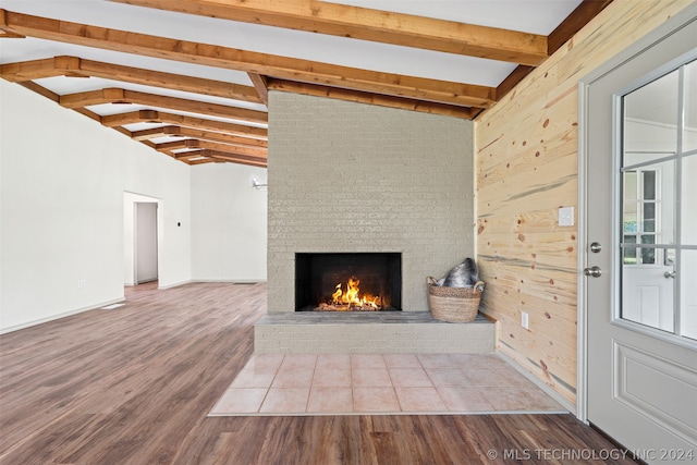 unfurnished living room featuring hardwood / wood-style floors, wooden walls, and lofted ceiling with beams