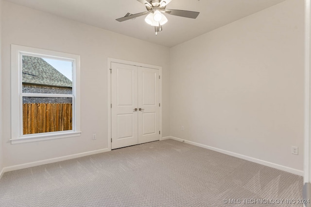 unfurnished bedroom featuring ceiling fan, light carpet, and a closet