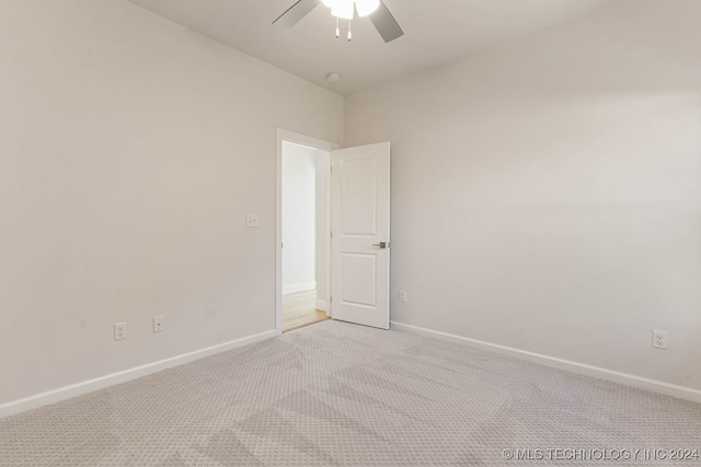 spare room with ceiling fan and light colored carpet