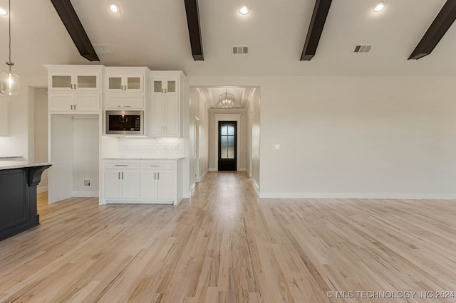 unfurnished living room with vaulted ceiling with beams, light wood-type flooring, and an inviting chandelier