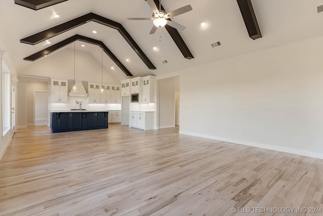 unfurnished living room with beam ceiling, high vaulted ceiling, and light wood-type flooring