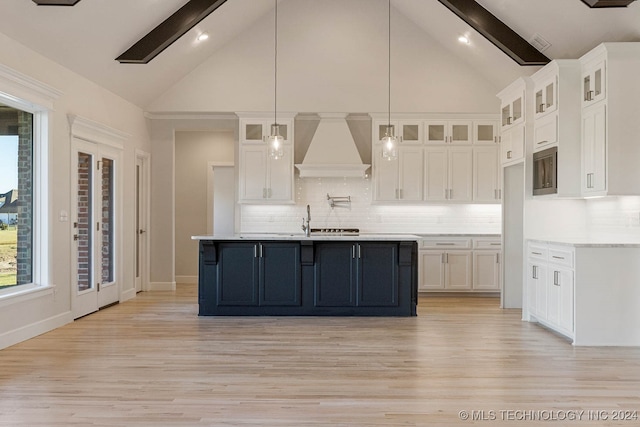 kitchen featuring tasteful backsplash, white cabinetry, high vaulted ceiling, and premium range hood