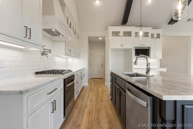 kitchen featuring white cabinets, decorative light fixtures, stainless steel appliances, and premium range hood