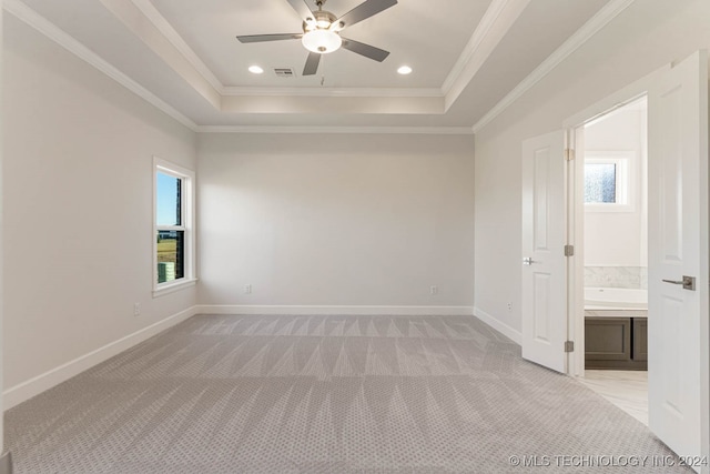 empty room with light carpet, a tray ceiling, ceiling fan, and crown molding