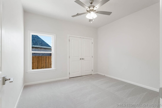 unfurnished bedroom with light colored carpet, ceiling fan, and a closet