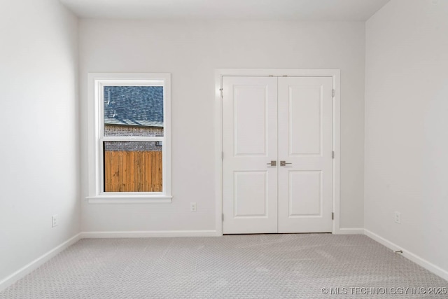 unfurnished bedroom featuring light carpet and a closet