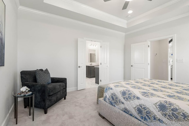 bedroom with ornamental molding, light colored carpet, ceiling fan, a tray ceiling, and ensuite bath