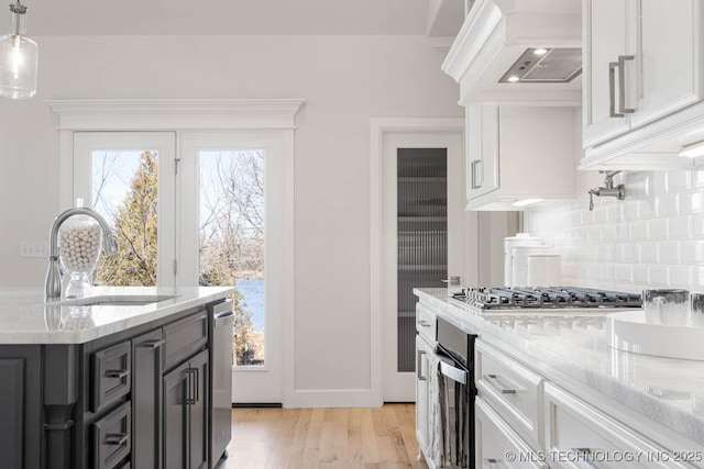 kitchen featuring sink, custom exhaust hood, decorative light fixtures, stainless steel appliances, and white cabinets