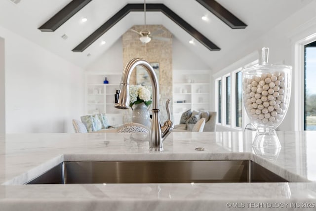 room details with beamed ceiling, a skylight, sink, and light stone counters