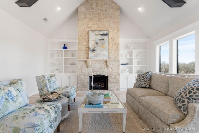 living room featuring hardwood / wood-style flooring, a stone fireplace, high vaulted ceiling, and built in features