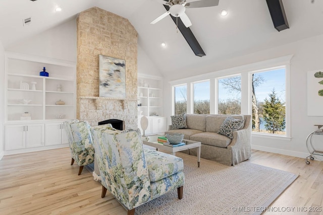 living room with built in features, high vaulted ceiling, a fireplace, ceiling fan, and light wood-type flooring