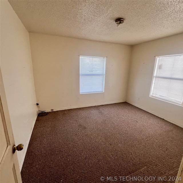 empty room with carpet and a textured ceiling