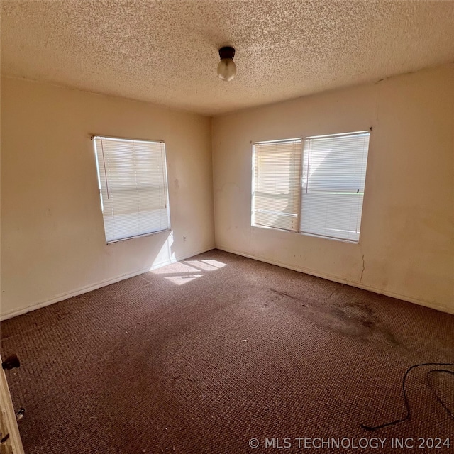 carpeted empty room featuring a textured ceiling