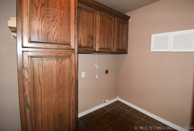 laundry area featuring dark tile floors, cabinets, and electric dryer hookup