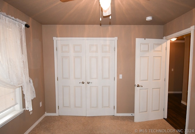 unfurnished bedroom with ceiling fan, a closet, and carpet flooring