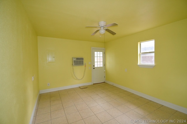 tiled spare room with a wall unit AC and ceiling fan