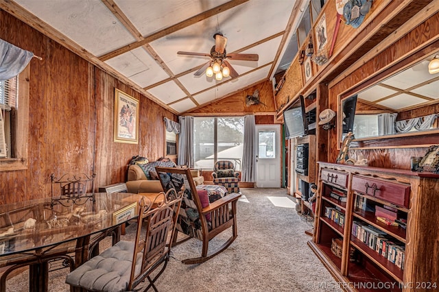 carpeted living room with lofted ceiling, wooden walls, and ceiling fan