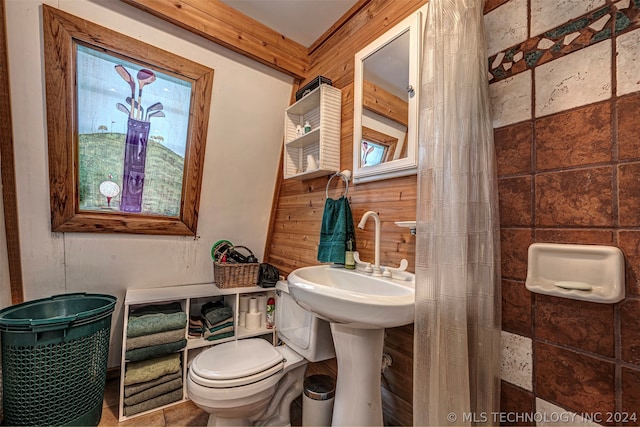 bathroom featuring tile floors, wooden walls, and toilet