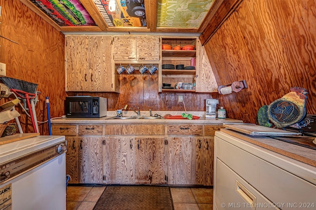 kitchen with sink, wooden walls, light tile flooring, and fridge