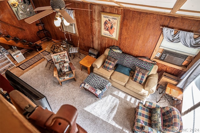 carpeted living room featuring ceiling fan and wood walls