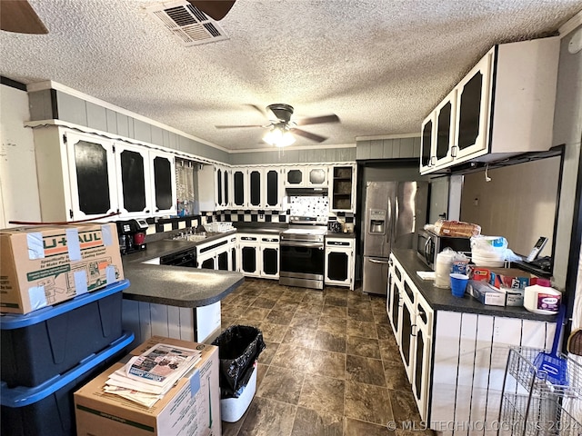 kitchen featuring appliances with stainless steel finishes, dark tile flooring, ceiling fan, and a textured ceiling