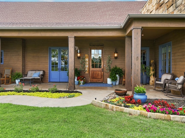 property entrance with a shingled roof, french doors, and a yard