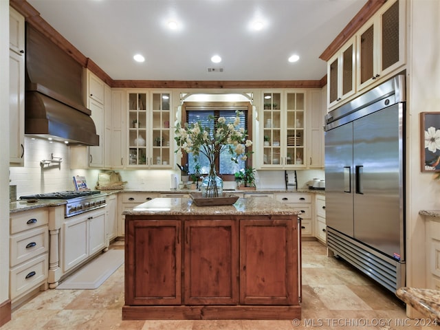 kitchen featuring light stone countertops, appliances with stainless steel finishes, a center island, and white cabinetry