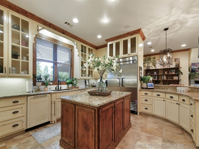 kitchen featuring pendant lighting, dishwasher, cream cabinets, sink, and stainless steel built in refrigerator