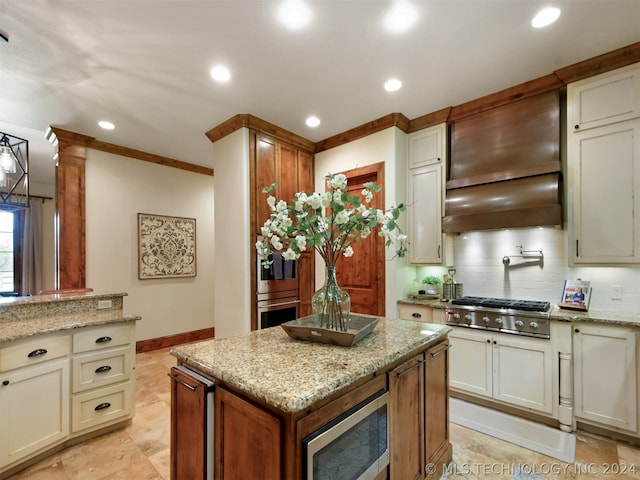 kitchen with decorative columns, backsplash, light stone countertops, and stainless steel appliances