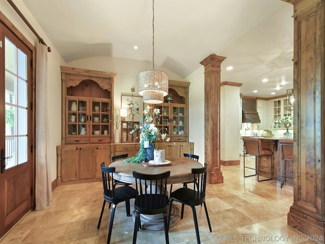 dining room with decorative columns, lofted ceiling, and a notable chandelier