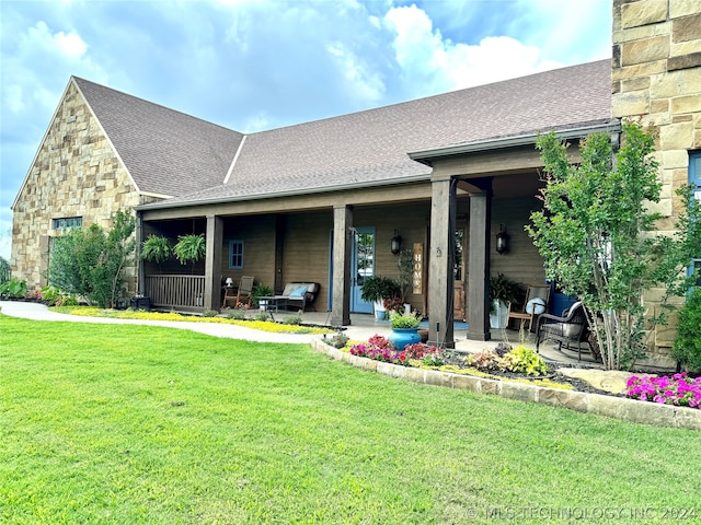 rear view of property with covered porch and a lawn