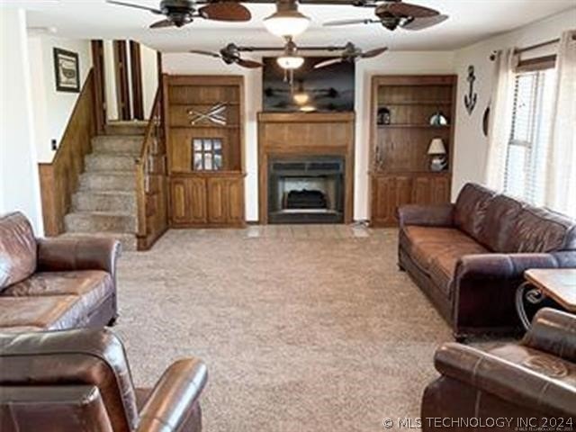 carpeted living room with built in features and ceiling fan