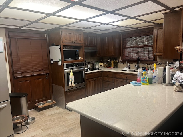 kitchen featuring stainless steel appliances, dark brown cabinets, exhaust hood, a drop ceiling, and light tile floors