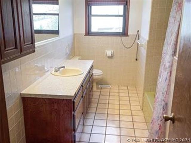 full bathroom featuring plenty of natural light, tile walls, toilet, and vanity