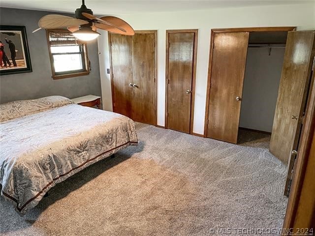 carpeted bedroom with ceiling fan and multiple closets