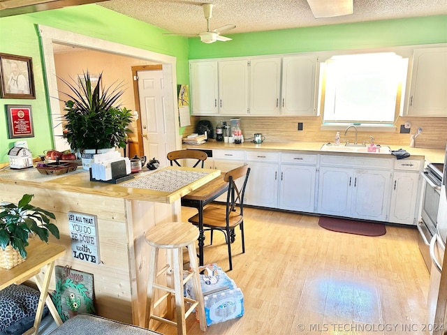 kitchen with white cabinetry, ceiling fan, a textured ceiling, and light hardwood / wood-style flooring