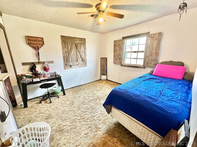 carpeted bedroom featuring ceiling fan and a textured ceiling