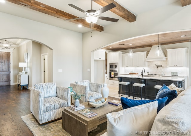 living room featuring beamed ceiling, ceiling fan, sink, and dark wood-type flooring