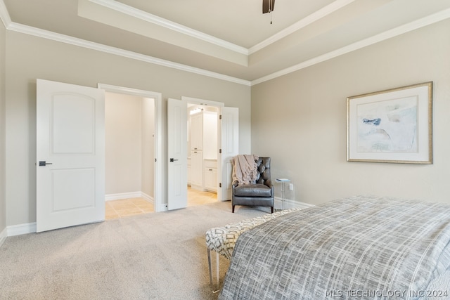 bedroom with ceiling fan, a tray ceiling, crown molding, light carpet, and ensuite bath