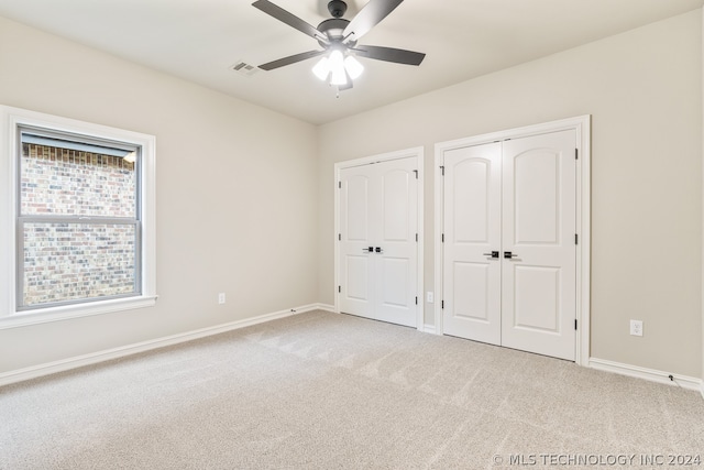 unfurnished bedroom featuring two closets, carpet, and ceiling fan