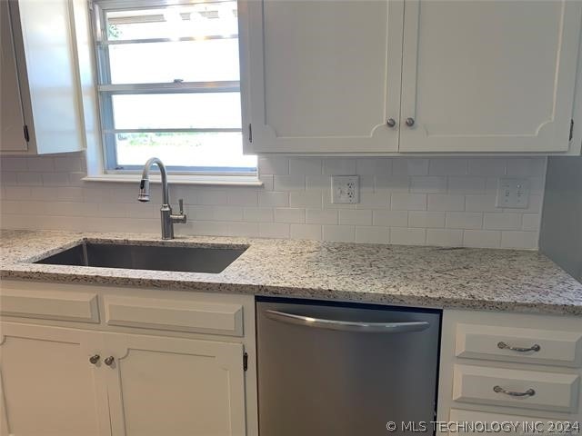 kitchen with sink, white cabinets, tasteful backsplash, and stainless steel dishwasher