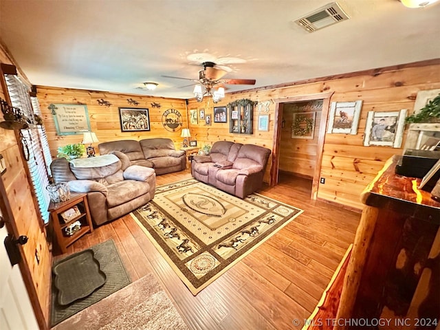 living room with wood walls, hardwood / wood-style flooring, and ceiling fan