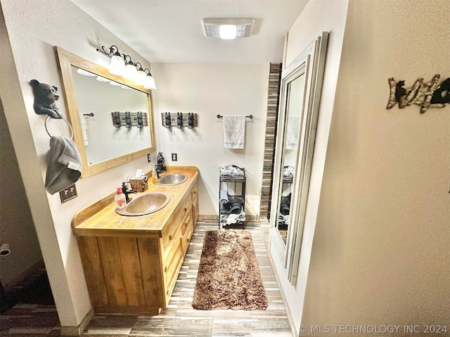 bathroom with dual bowl vanity and hardwood / wood-style flooring