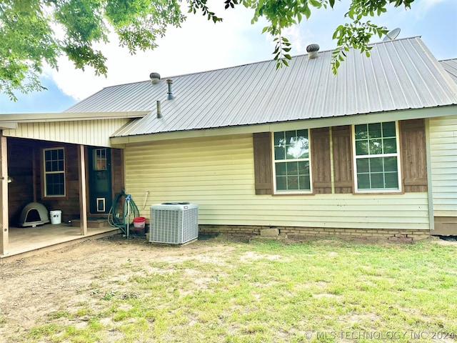 back of property featuring central AC and a yard