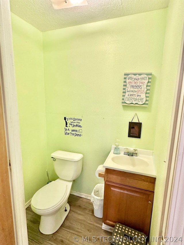 bathroom featuring toilet, vanity, hardwood / wood-style flooring, and a textured ceiling