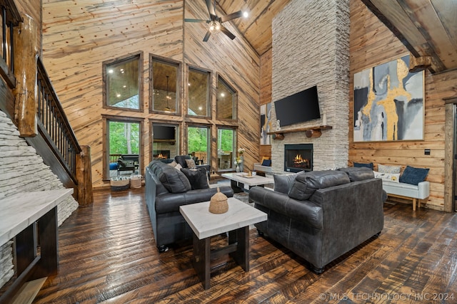 living room with high vaulted ceiling, dark wood-type flooring, a stone fireplace, and wood walls