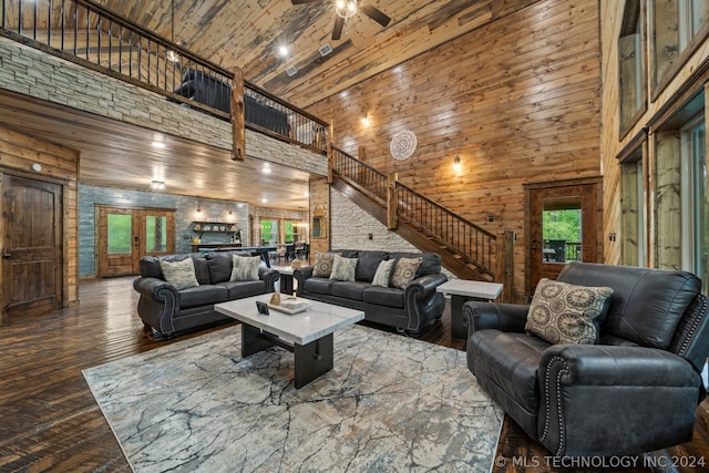 living room with ceiling fan, wood ceiling, dark wood-type flooring, high vaulted ceiling, and wood walls