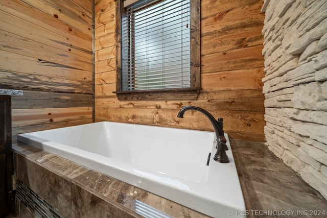 bathroom featuring a relaxing tiled bath and wooden walls