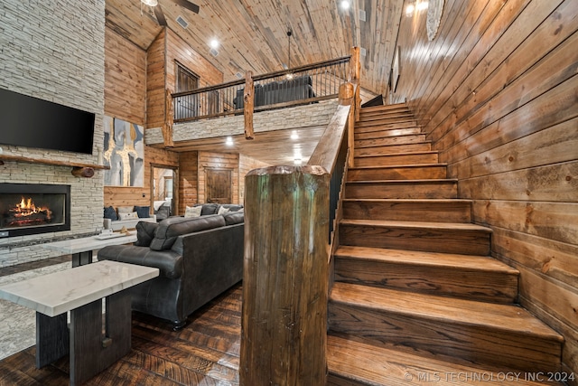 stairway featuring ceiling fan, a fireplace, wood ceiling, and dark wood-type flooring